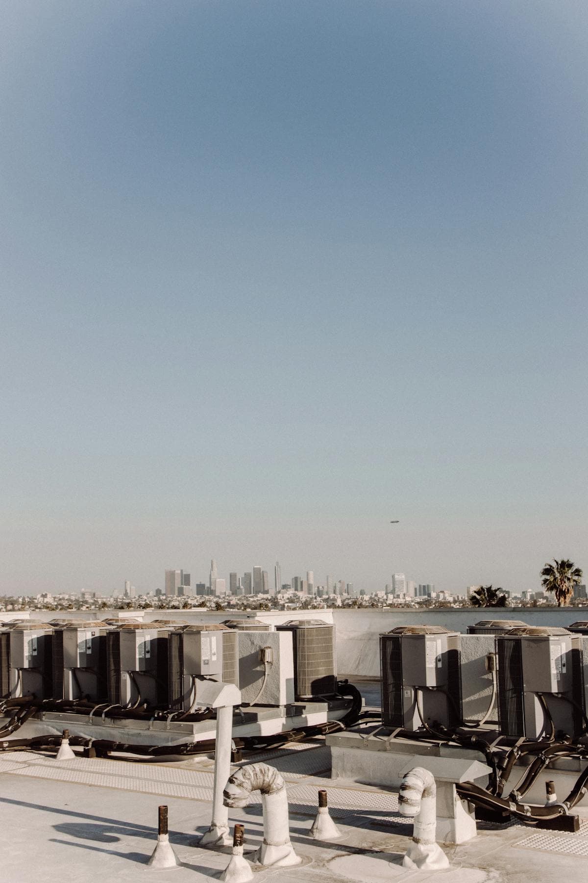 A row of rooftop HVAC package units under a clear blue sky
